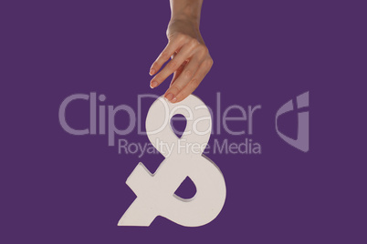 Female hand holding up an ampersand from the top