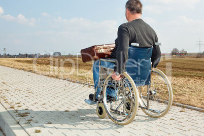 Man with suitcase wheelchair and walk on the road