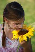 Mädchen riecht an einer Sonnenblume