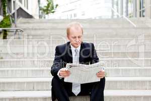 Junger geschäftsmann liest eine Zeitung vor einem Gebäude