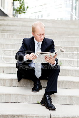 Junger geschäftsmann liest eine Zeitung vor einem Gebäude