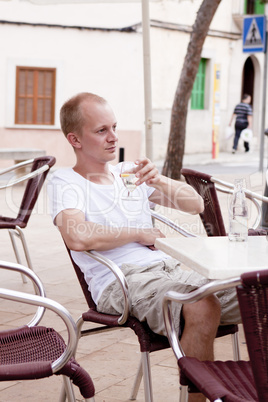 Junger mann sitzt in einem Cafe im freien