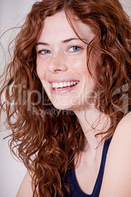 junge hübsche Frau mit Sommersprossen und lockigen harren lacht