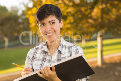 Mixed Race Young Female Holding Sketch Book and Pencil Outdoors