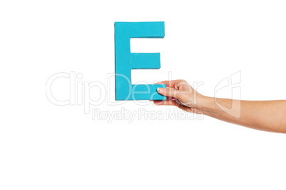 hand holding up the letter E from the right