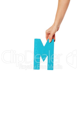 hand holding up the letter M from the top