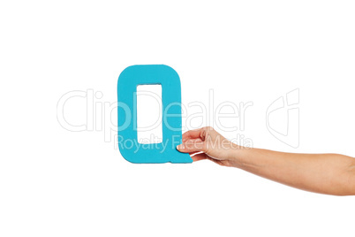 hand holding up the letter Q from the right