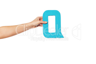 hand holding up the letter Q from the left