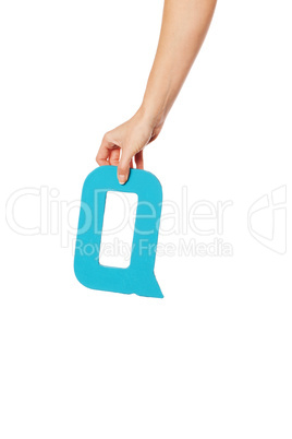 hand holding up the letter Q from the top