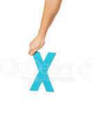 hand holding up the letter X from the top