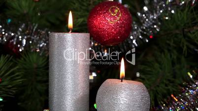 candle lit in front of festive lights Christmas tree