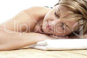 Young woman enjoying hot stone spa treatment