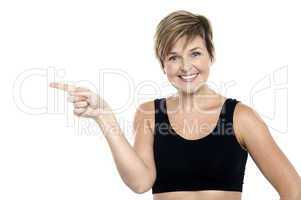 Cheerful middle aged woman pointing at copy space area