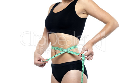 Fit woman measuring her waist, cropped image