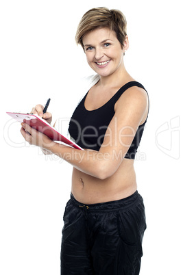 Female gym instructor writing diet chart