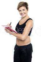 Female gym instructor writing diet chart