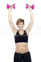 Mid adult woman holding dumbbells over head