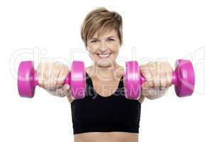 Lady holding pink dumbbells. Arms outstretched