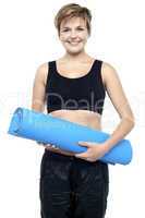Health conscious woman holding blue exercise mat