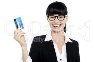 Cheerful bespectacled woman holding up her cash card
