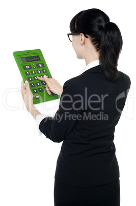 Rear view of corporate woman using green calculator