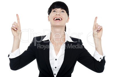 Excited businesswoman looking ad pointing upwards