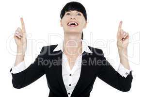 Excited businesswoman looking ad pointing upwards