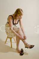 Frau im Sommerkleid bindet Sandalen