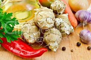 Jerusalem artichokes with vegetables and oil on board