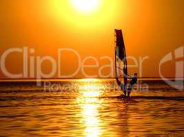 Silhouette of a windsurfer on waves of a gulf on a sunset