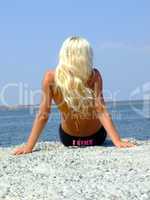 The girl-blonde sits on coast of a gulf