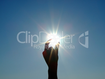 Silhouette of a female hand, the blue sky and the bright sun 2