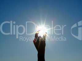 Silhouette of a female hand, the blue sky and the bright sun 2