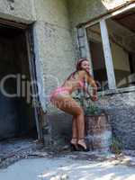The sexual girl in bikini with a bucket near the destroyed house