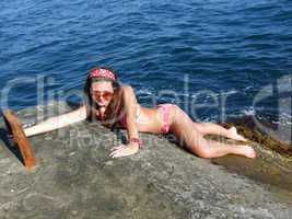 The sexual girl lays on a wharf on a background of the sea