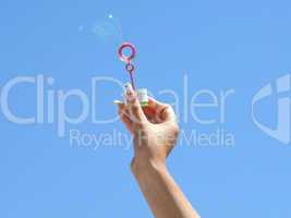 Female hand and soap bubbles on a background of the blue sky