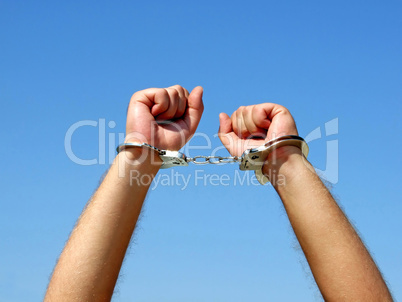 The hands of the men chained in handcuffs, on a background of th