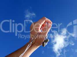 Hand with small headphones on a background of the blue sky