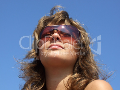 portrait of the girl in sunglasses on a background of the blue s