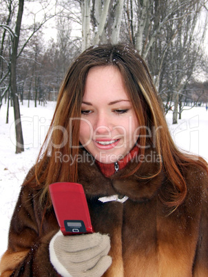 The girl in the winter in park with phone in a hand