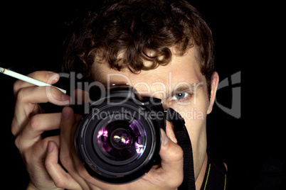 The young man - photographer behind work. Isolated on a black ba