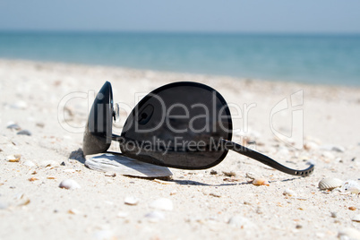 The black sunglasses lying on a beach