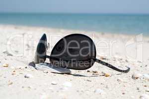 The black sunglasses lying on a beach