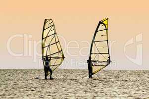 Silhouettes of two windsurfers on waves of a gulf