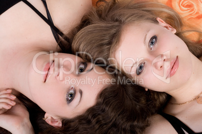 Portrait of the two beauty young women laying on a pillow 2