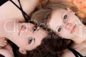 Portrait of the two beauty young women laying on a pillow 2