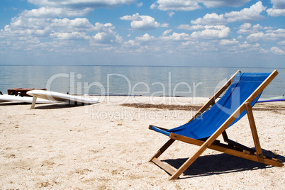Chair on a beach against a gulf and clouds