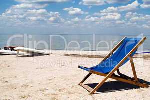Chair on a beach against a gulf and clouds