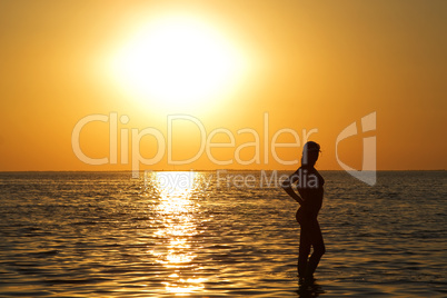 Silhouette of the young woman on a sea bay on a sunset