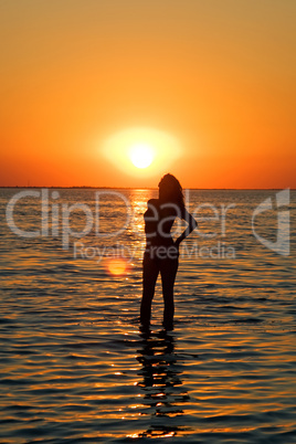 Silhouette of the young woman on a gulf on a sunset